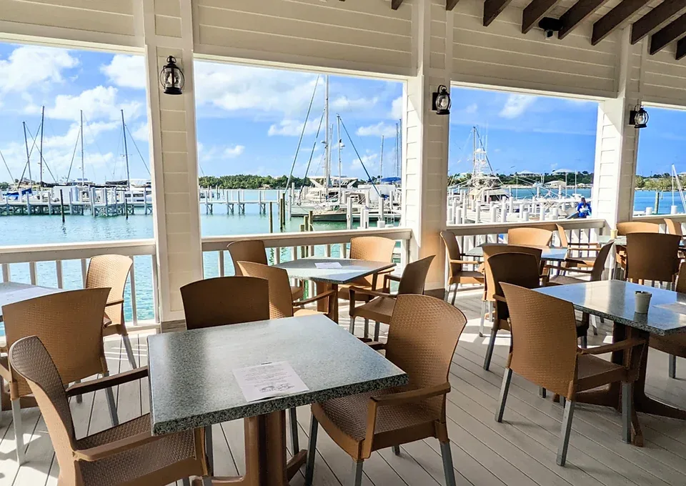 Representative hotel space: A covered dining patio overlooks a marina, with tables and seating beside the water.