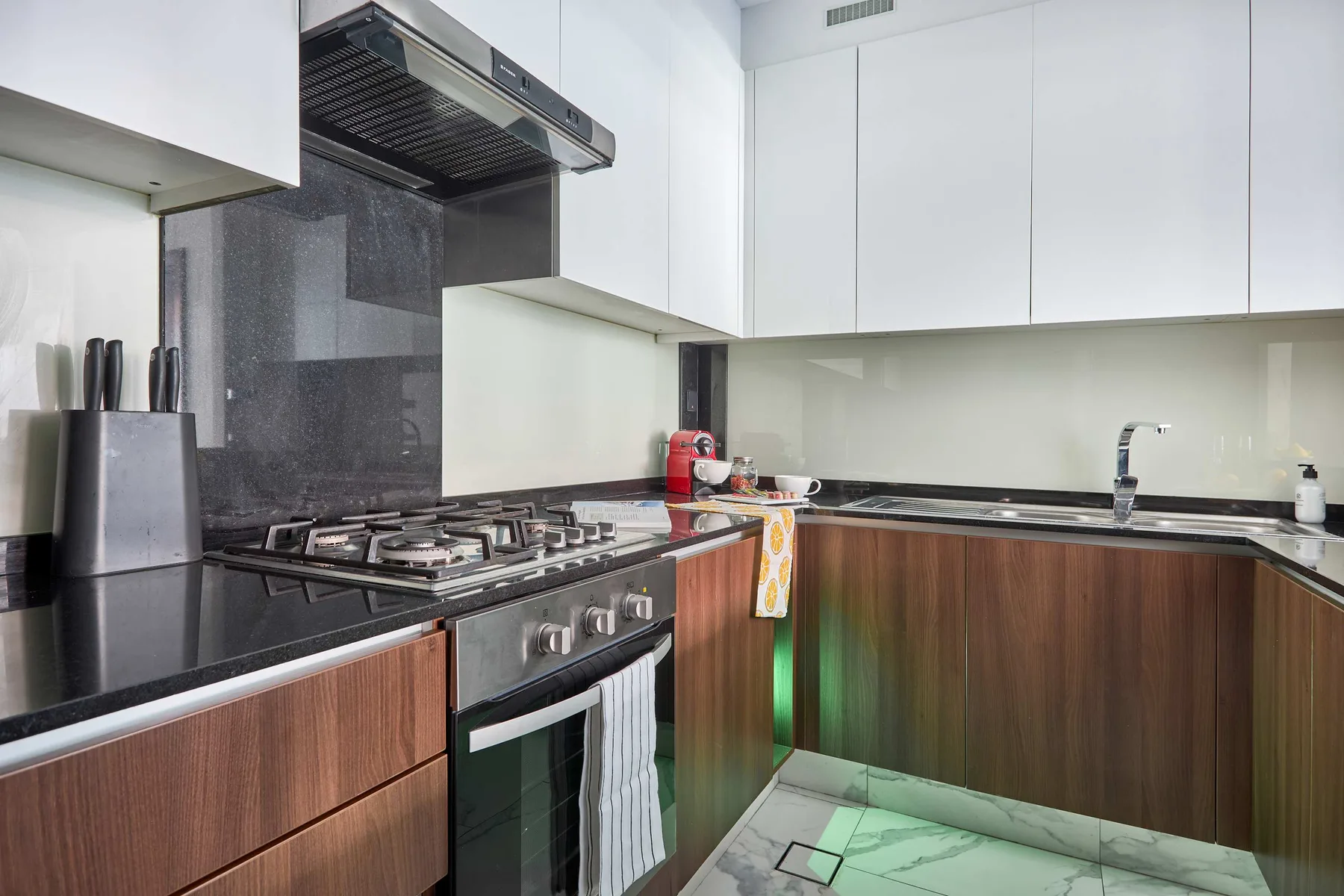 A modern kitchen with a gas cooktop, oven, and sink.