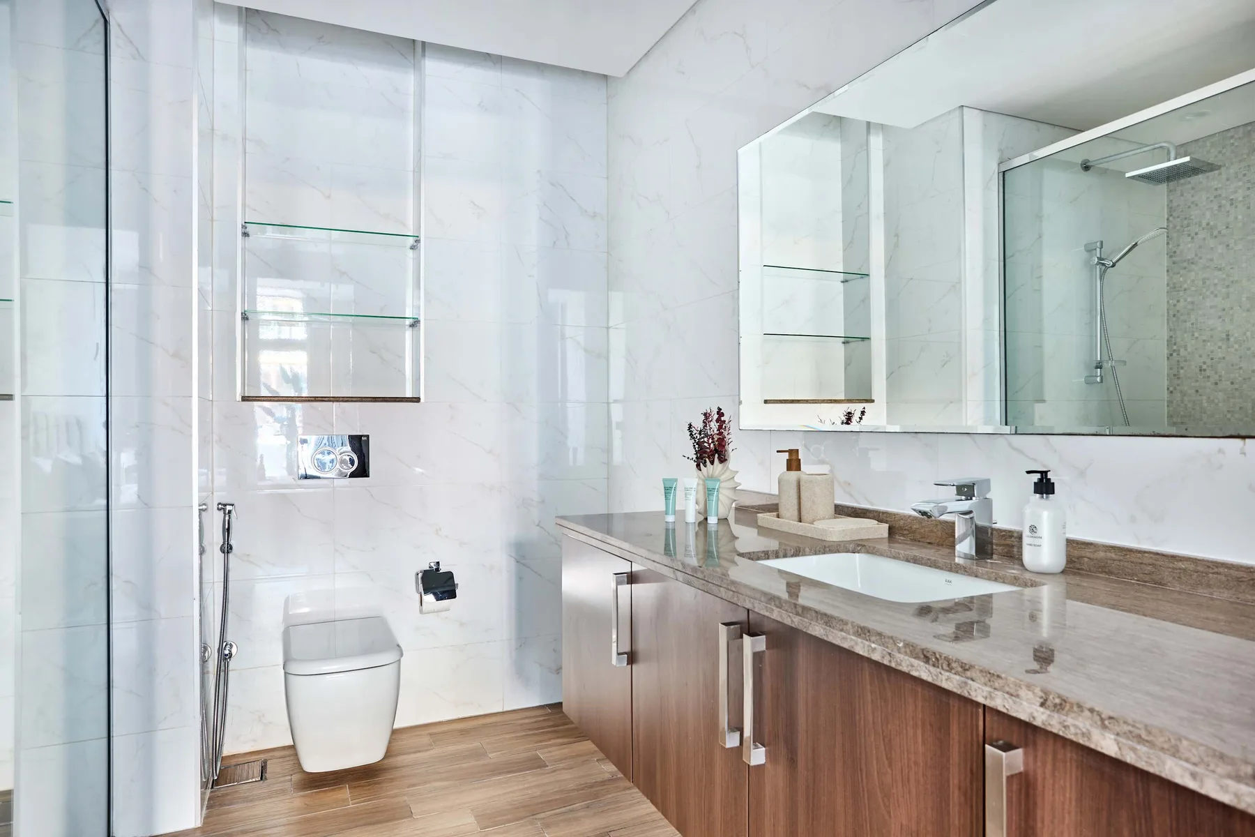 A bright bathroom with a toilet, vanity, and large mirror.