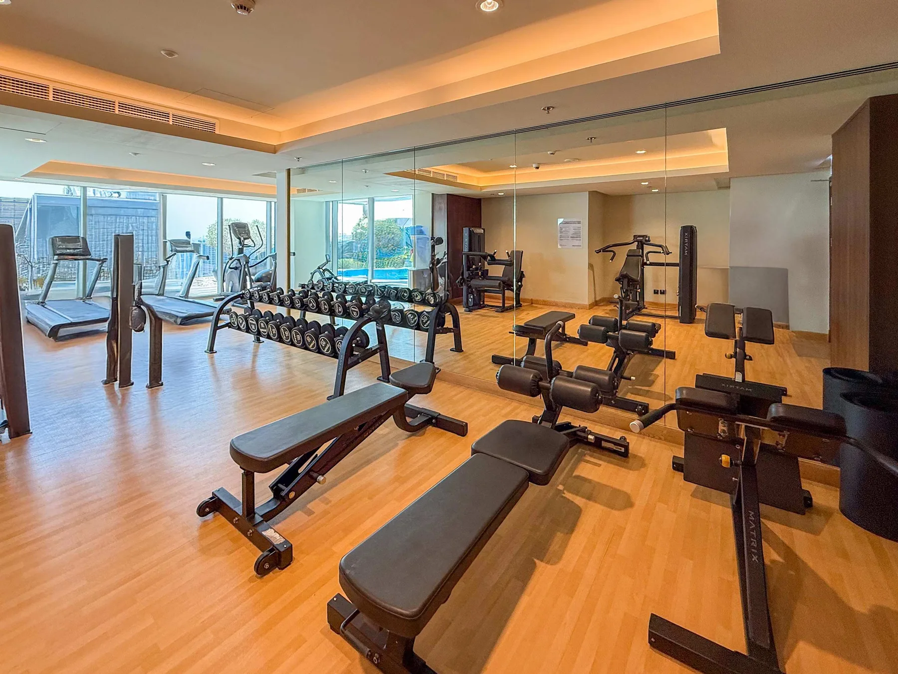 Shared amenity: A gym with exercise machines, weight benches, and dumbbells.