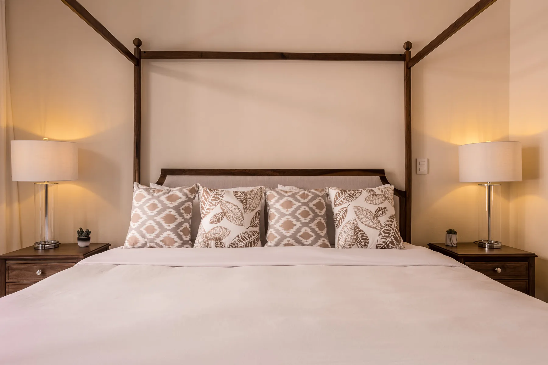 A bedroom with a large bed, patterned pillows, and matching bedside lamps.