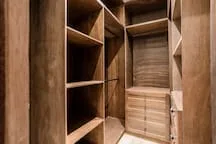 Un vestidor de madera con estantes abiertos y espacio para colgar ropa.
