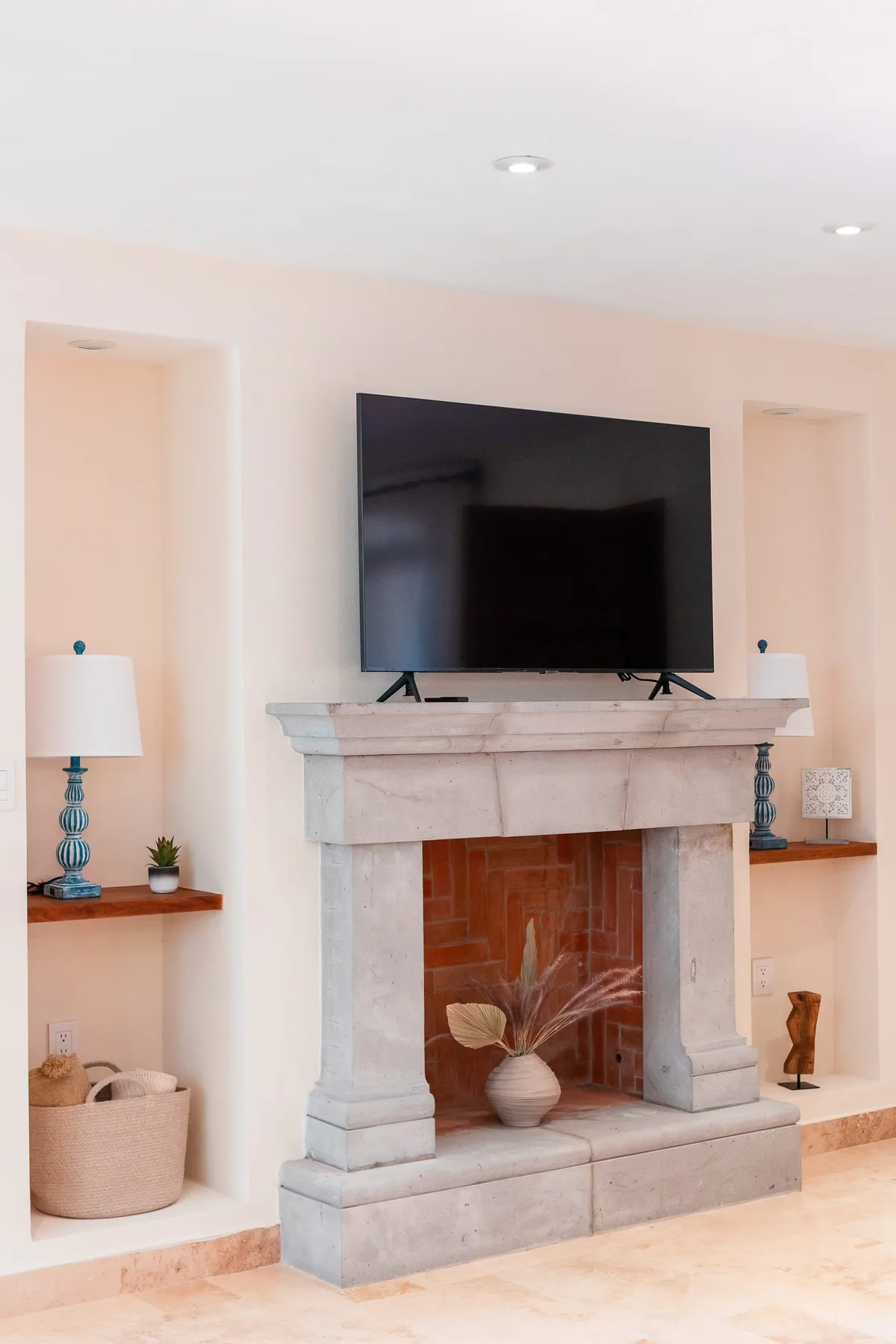 Una chimenea en la sala de estar con un televisor sobre la repisa.