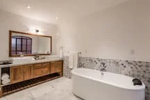Un baño luminoso cuenta con bañera, tocador y un gran espejo.