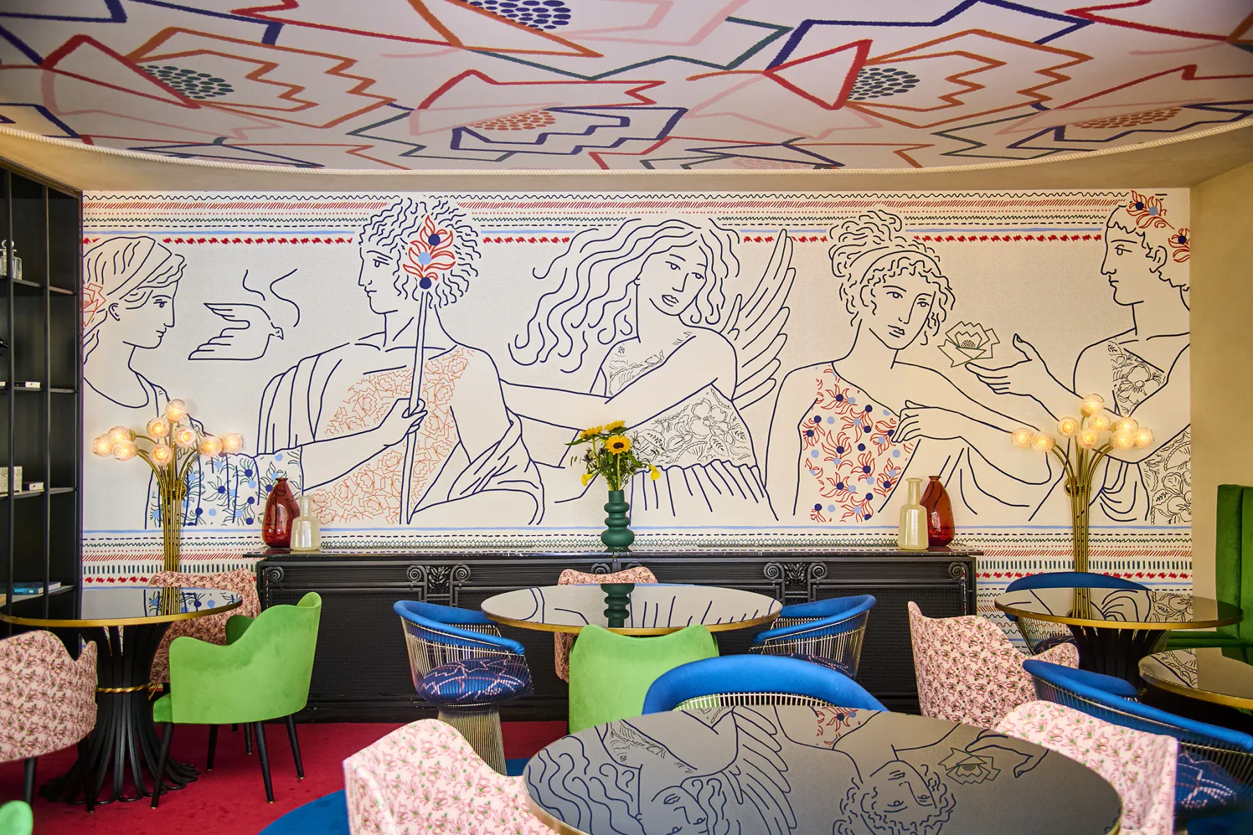 Espacio representativo del hotel: Un salón colorido con asientos estampados y una gran pared ilustrada.