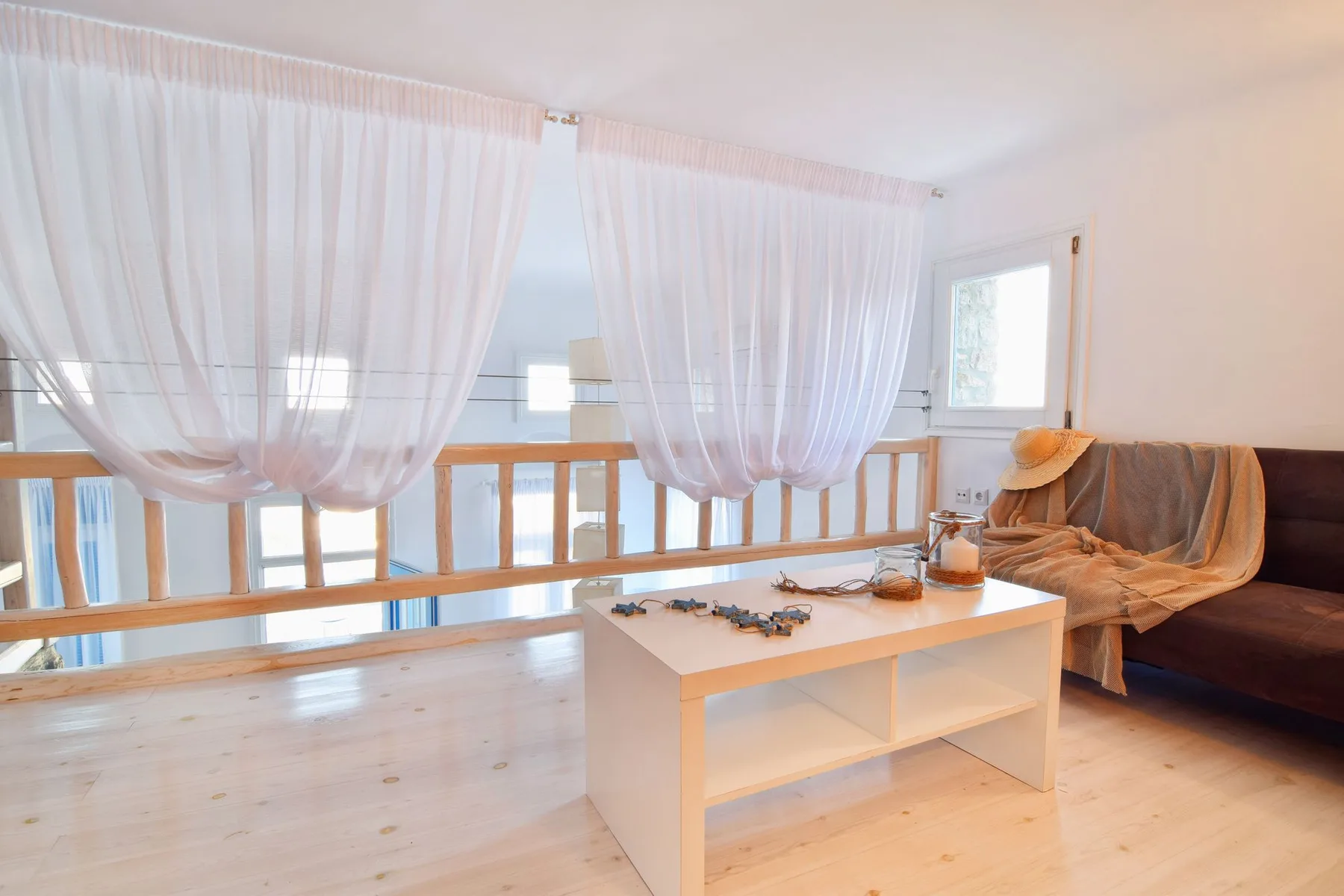 A bright living area with sheer curtains, a low table, and seating.