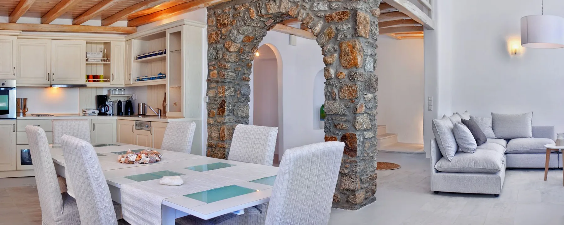 A dining area beside a stone archway and a living room with seating.