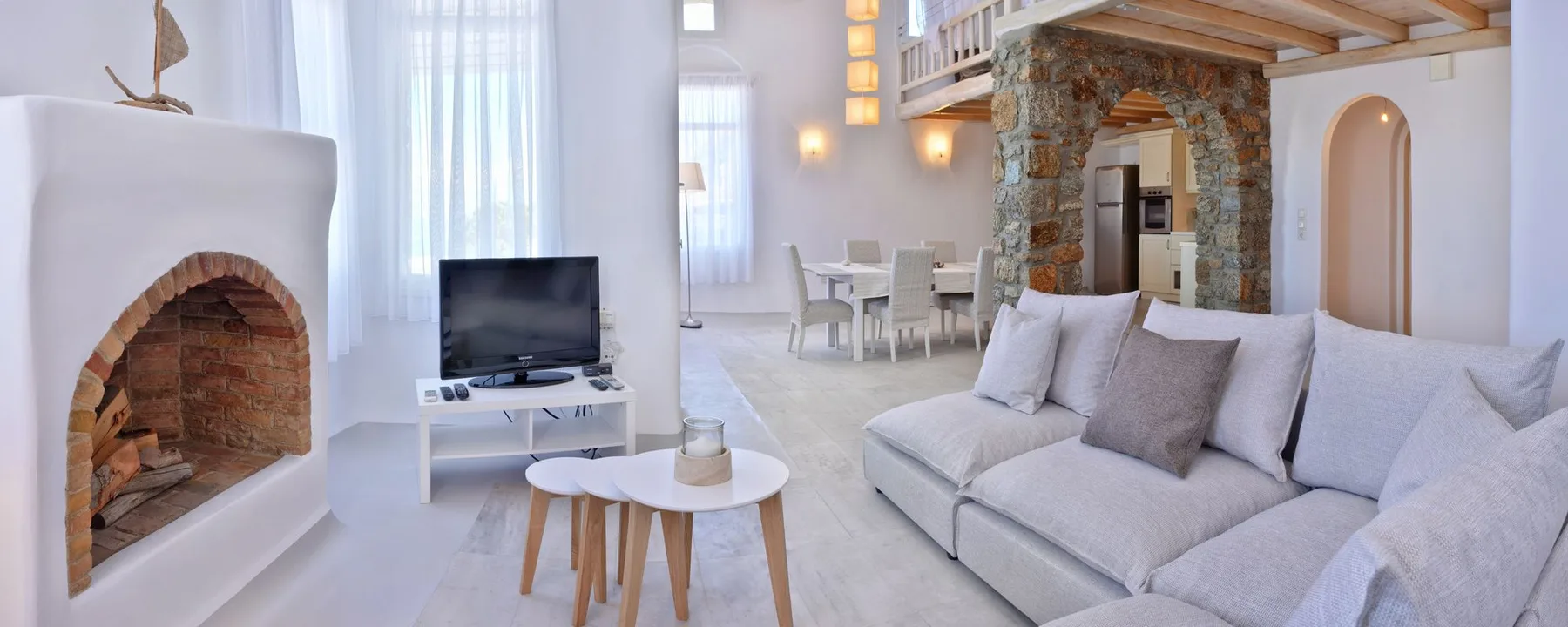 A bright living room with a white sectional sofa and stone fireplace.