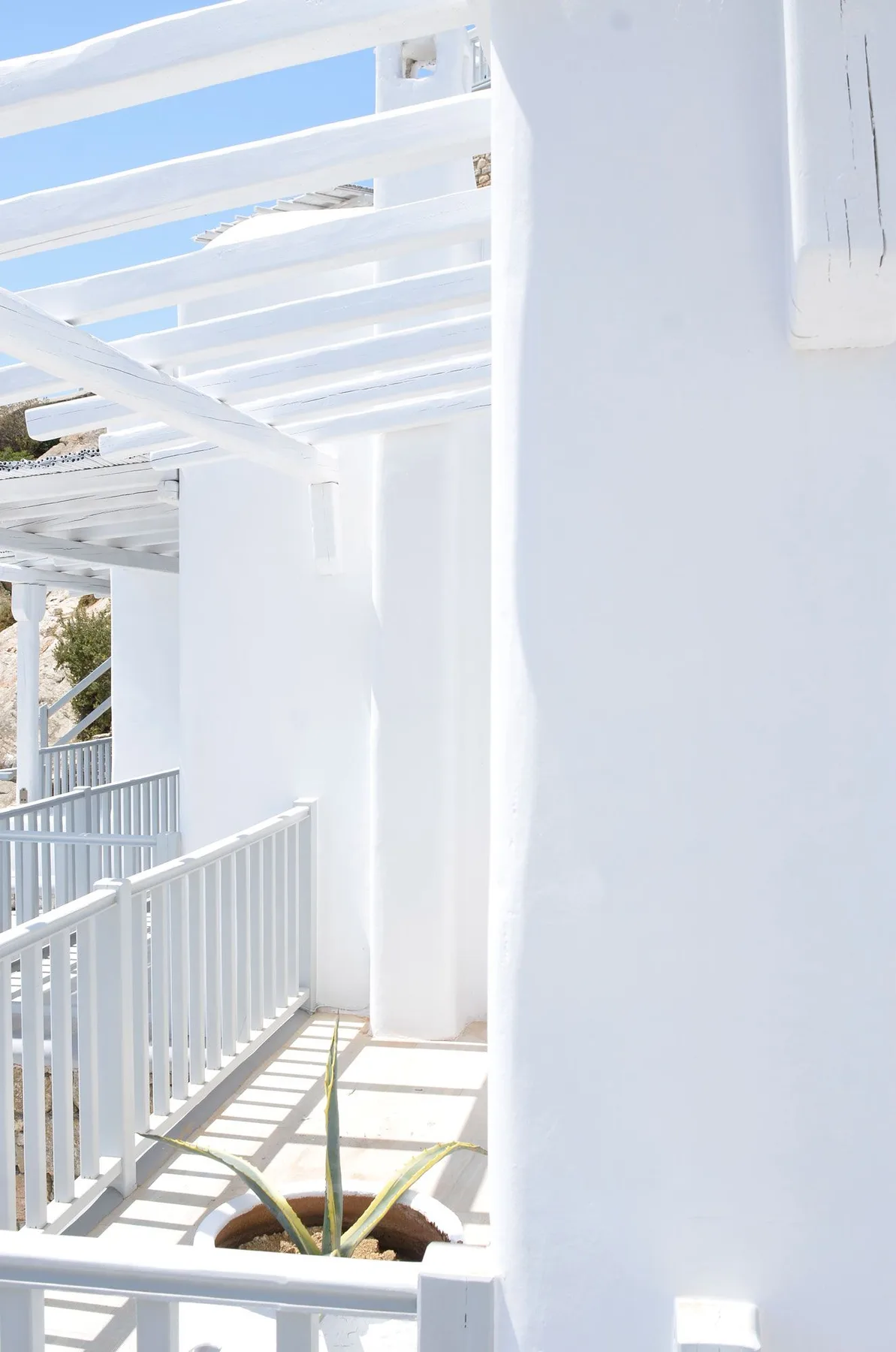A bright white outdoor walkway with railings and an overhead pergola.