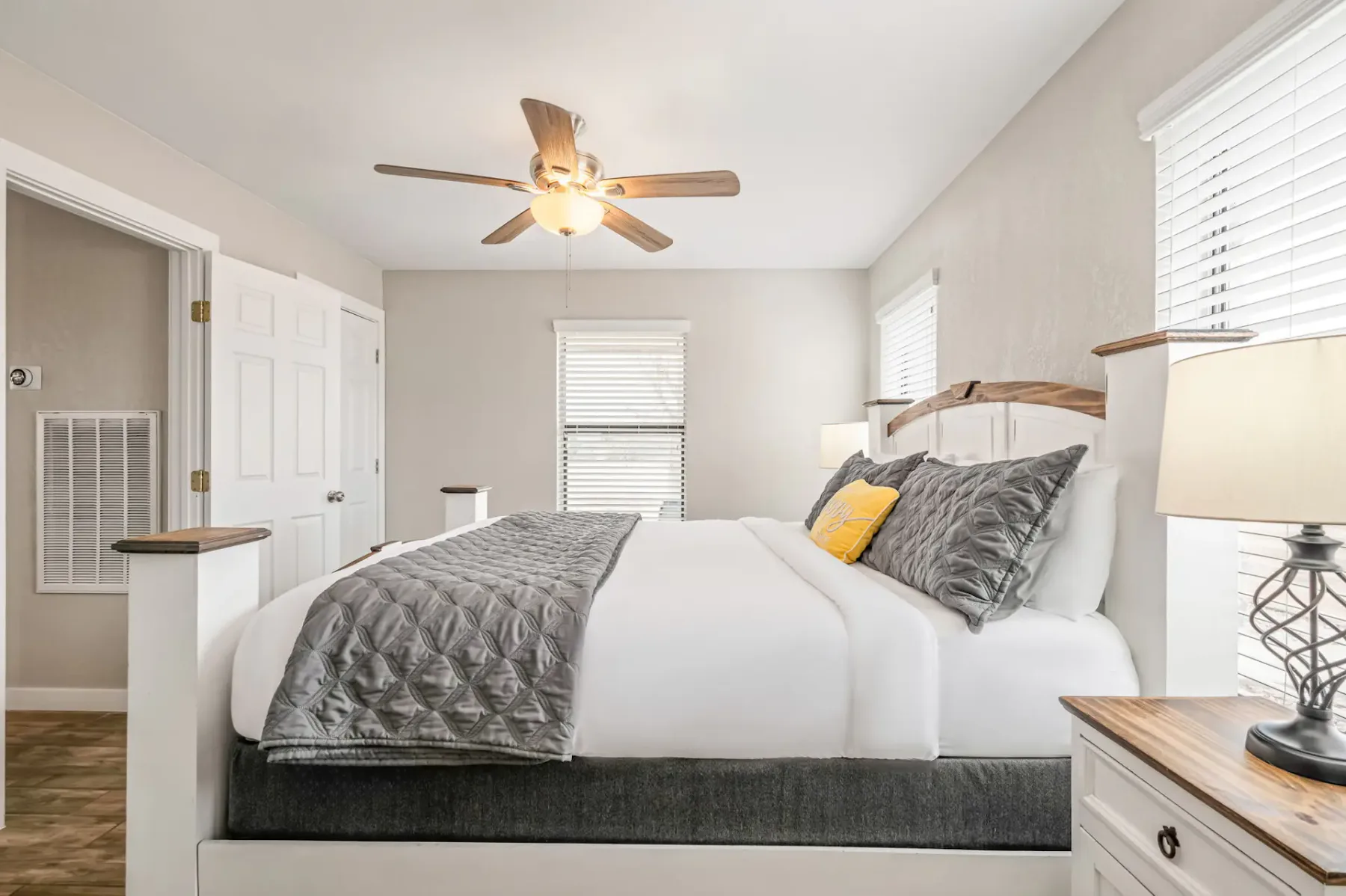 A bedroom with a neatly made bed and windows fitted with blinds.