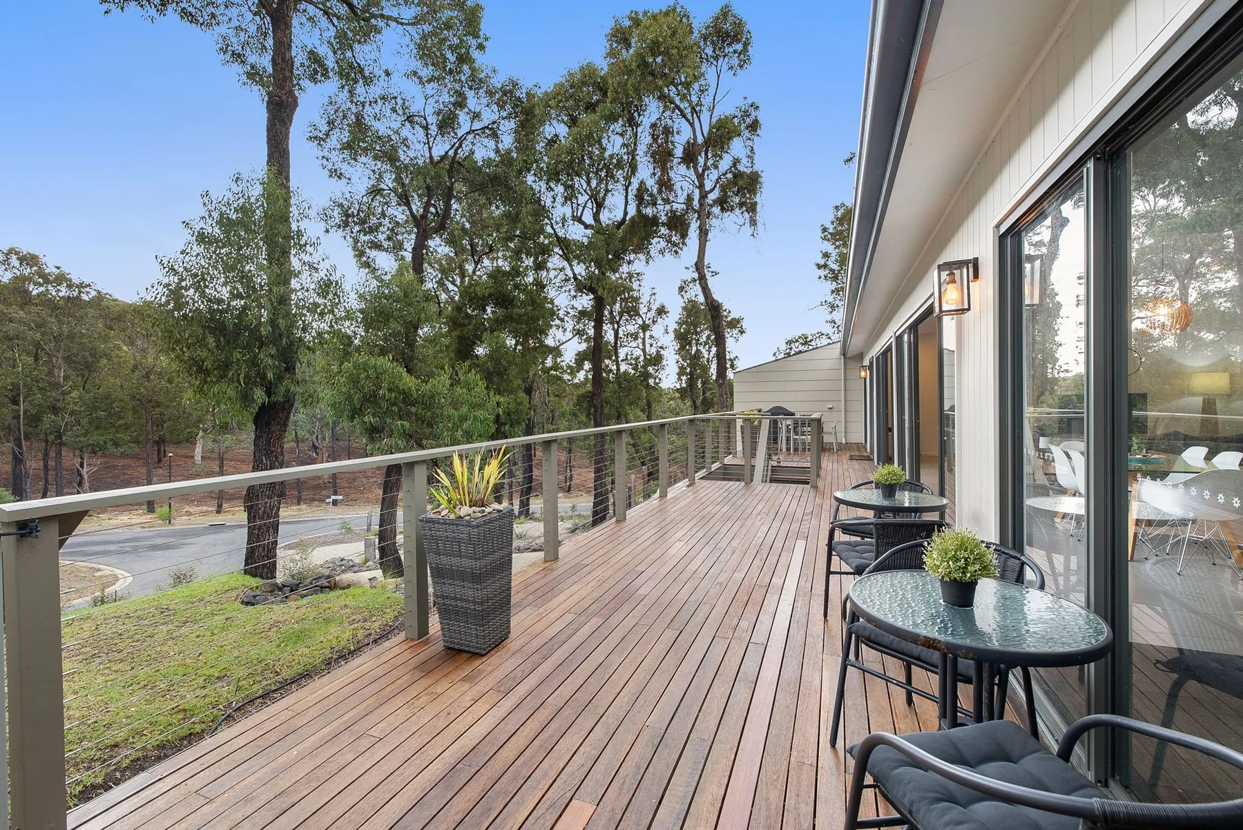 Una terraza de madera con asientos al aire libre da a un paisaje arbolado.