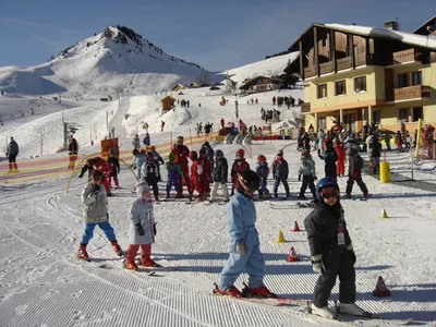 Representative hotel space: Skiers practice on a snowy slope beside a mountain resort building.