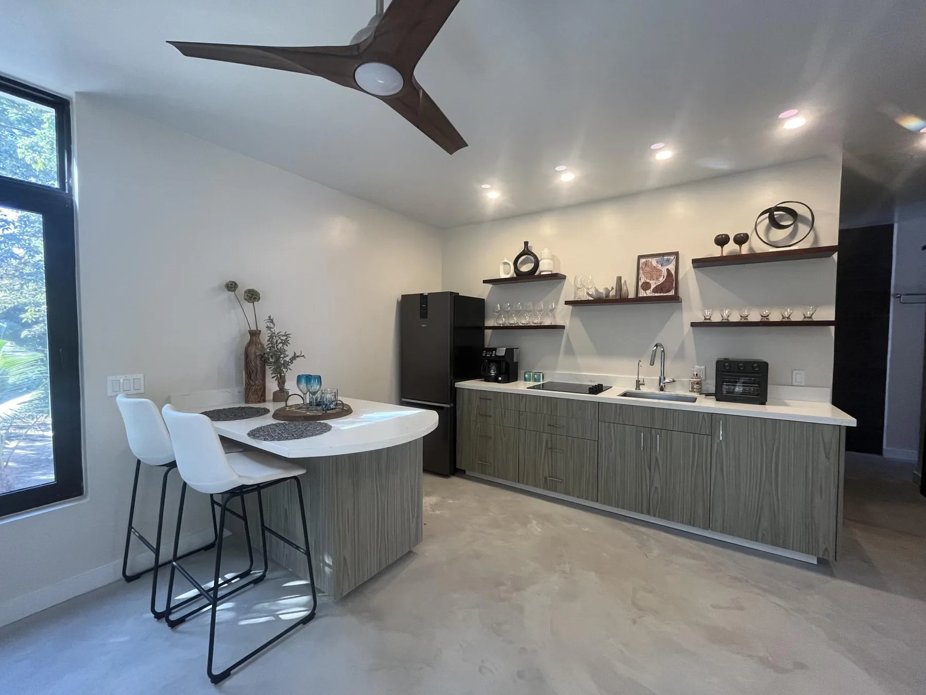 A modern kitchen with a peninsula, bar seating, and open shelves.