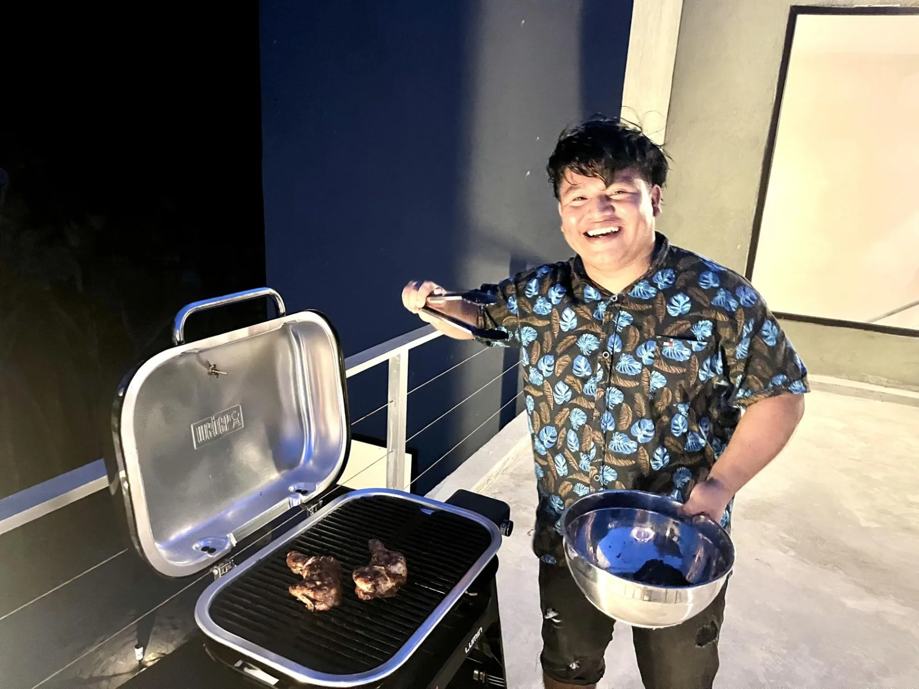 A person grills food on an outdoor patio at night.