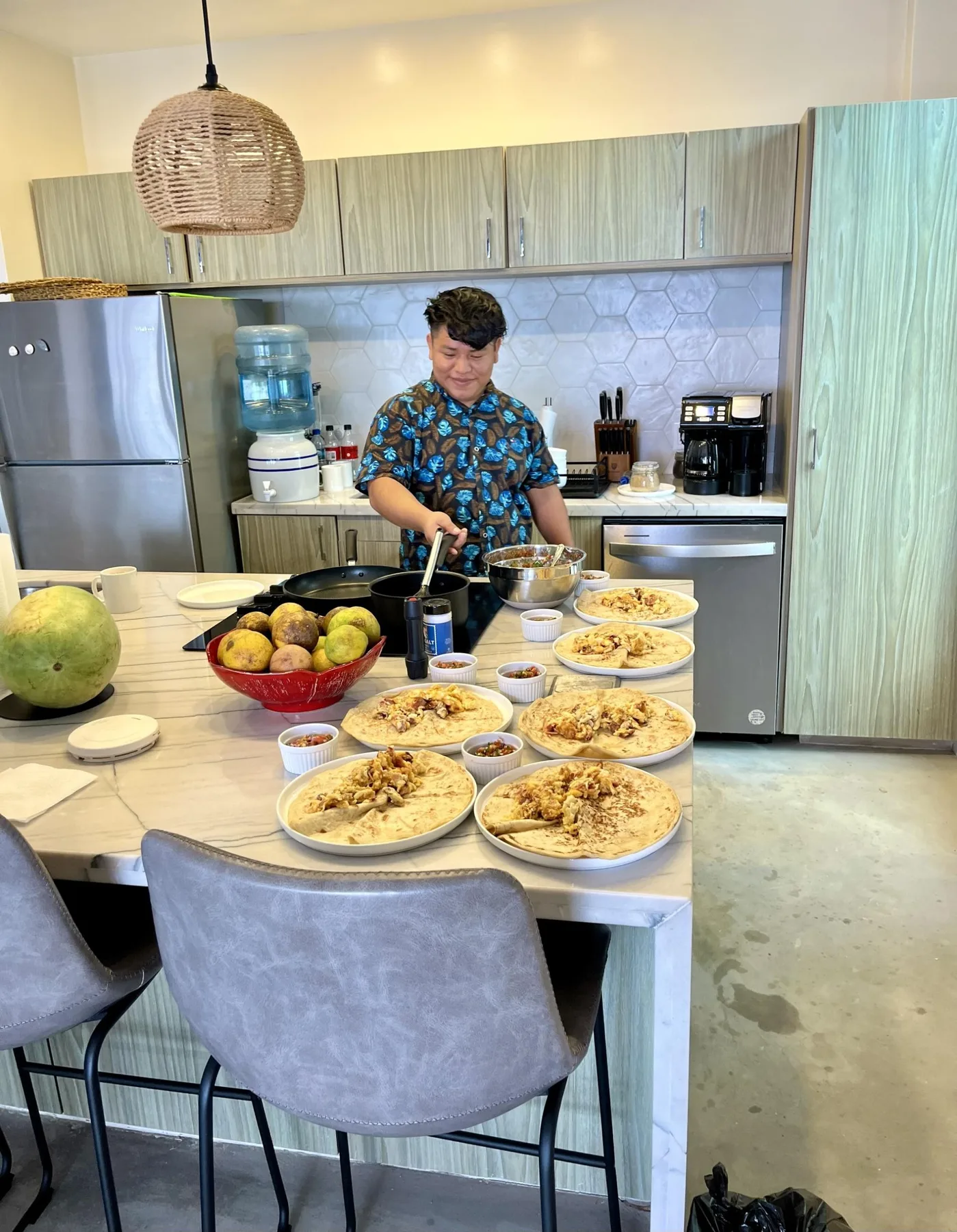 A man prepares food at a kitchen counter beside a table of plated meals.