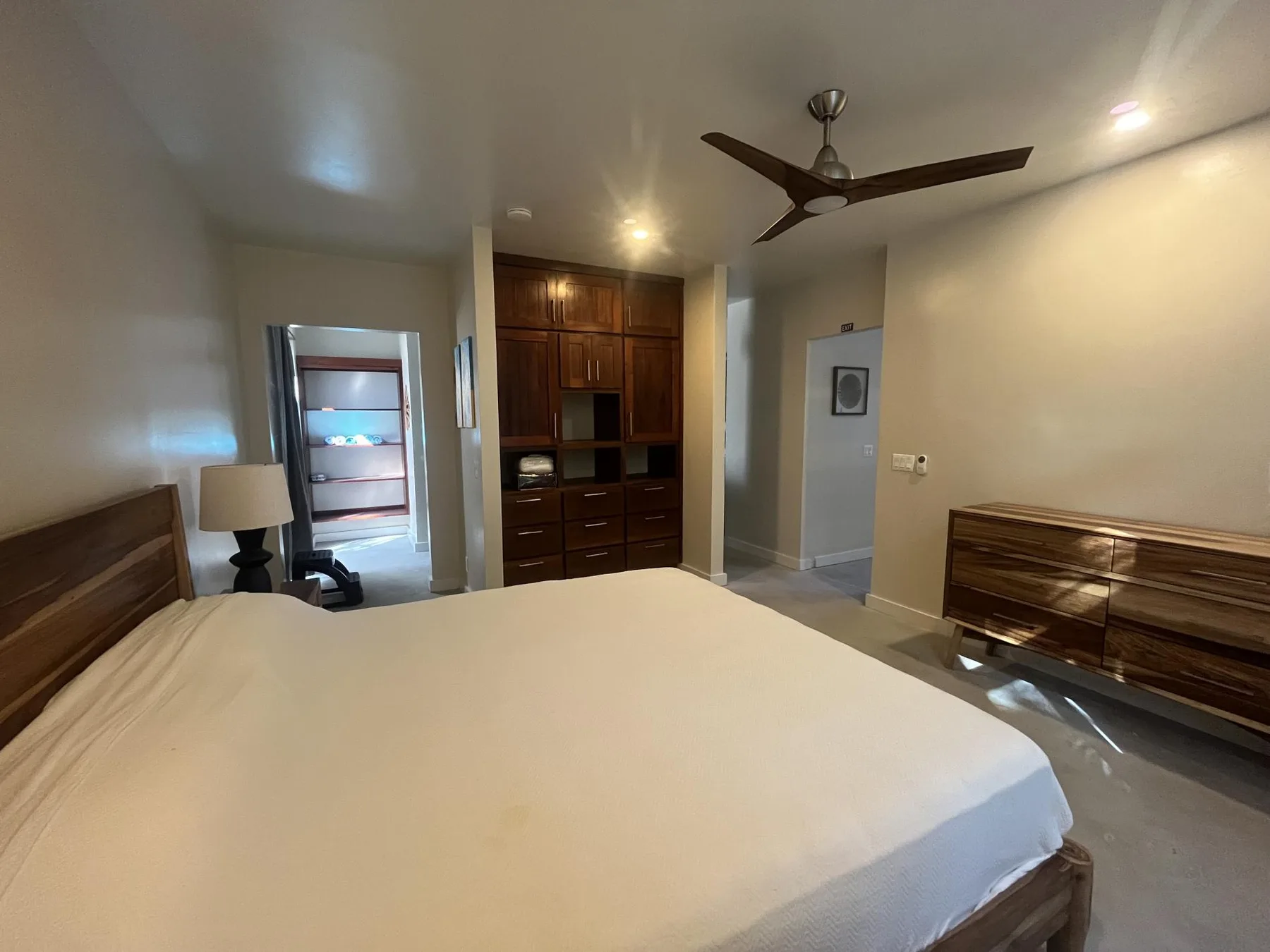 A bedroom with a large bed and dark wooden storage furniture.