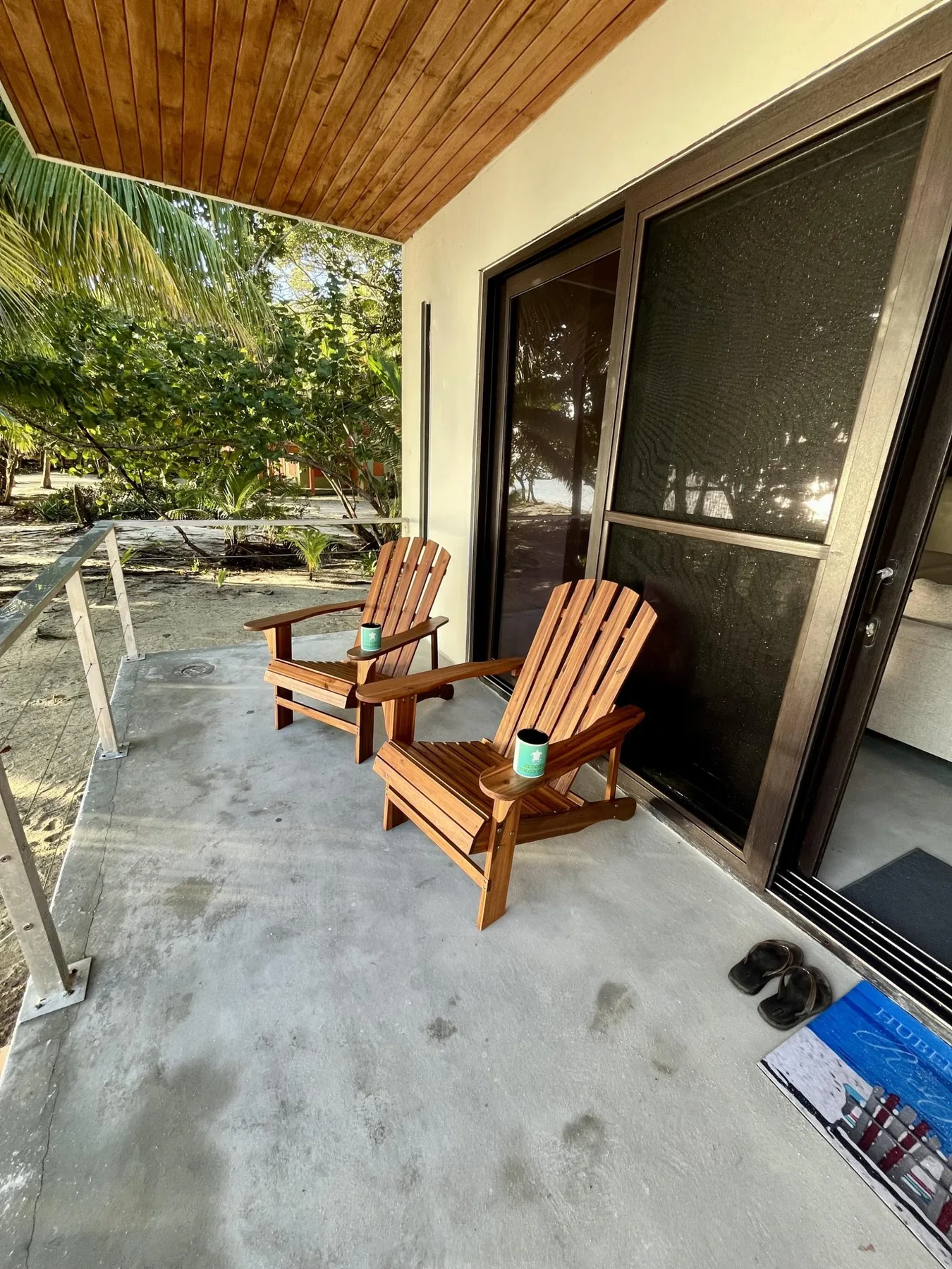 A covered outdoor patio with wooden seating beside a screened doorway.