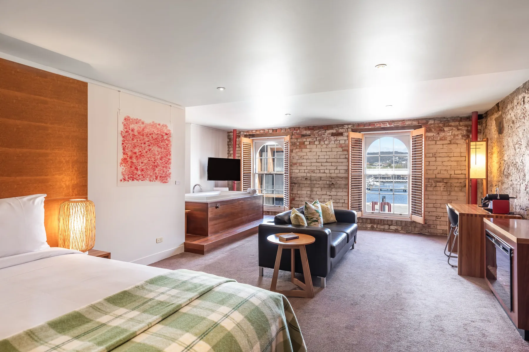 Representative hotel space: A bedroom and sitting area with a bed, seating, and exposed brick walls.