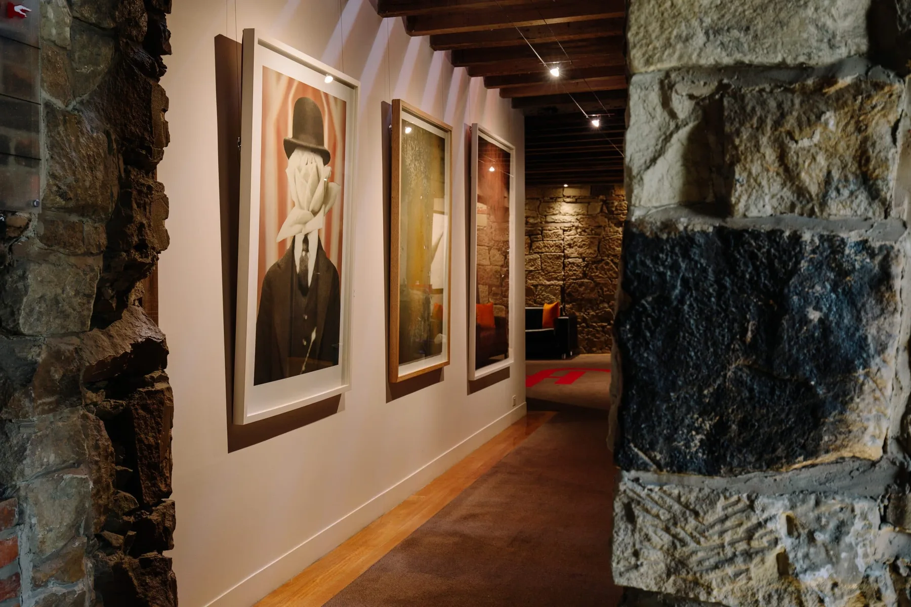 Representative hotel space: A gallery hallway displays framed artwork along a stone-lined passage.