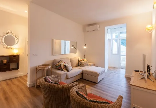 Una sala de estar con un sofá seccional y asientos de mimbre.