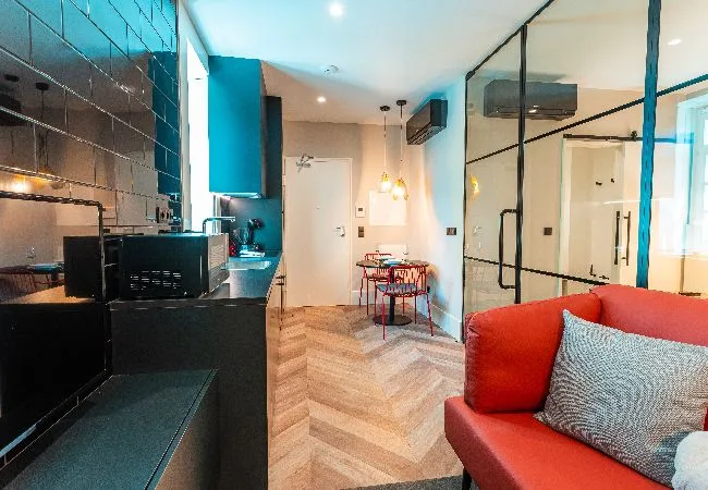 A compact modern living area with a red sofa and small dining table.