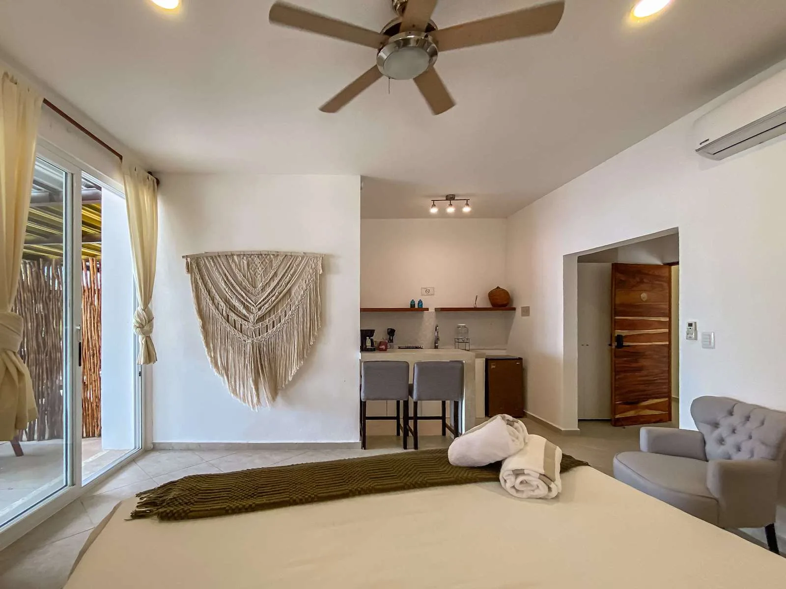 Un dormitorio con una cama, una pequeña cocina y puertas corredizas de vidrio.