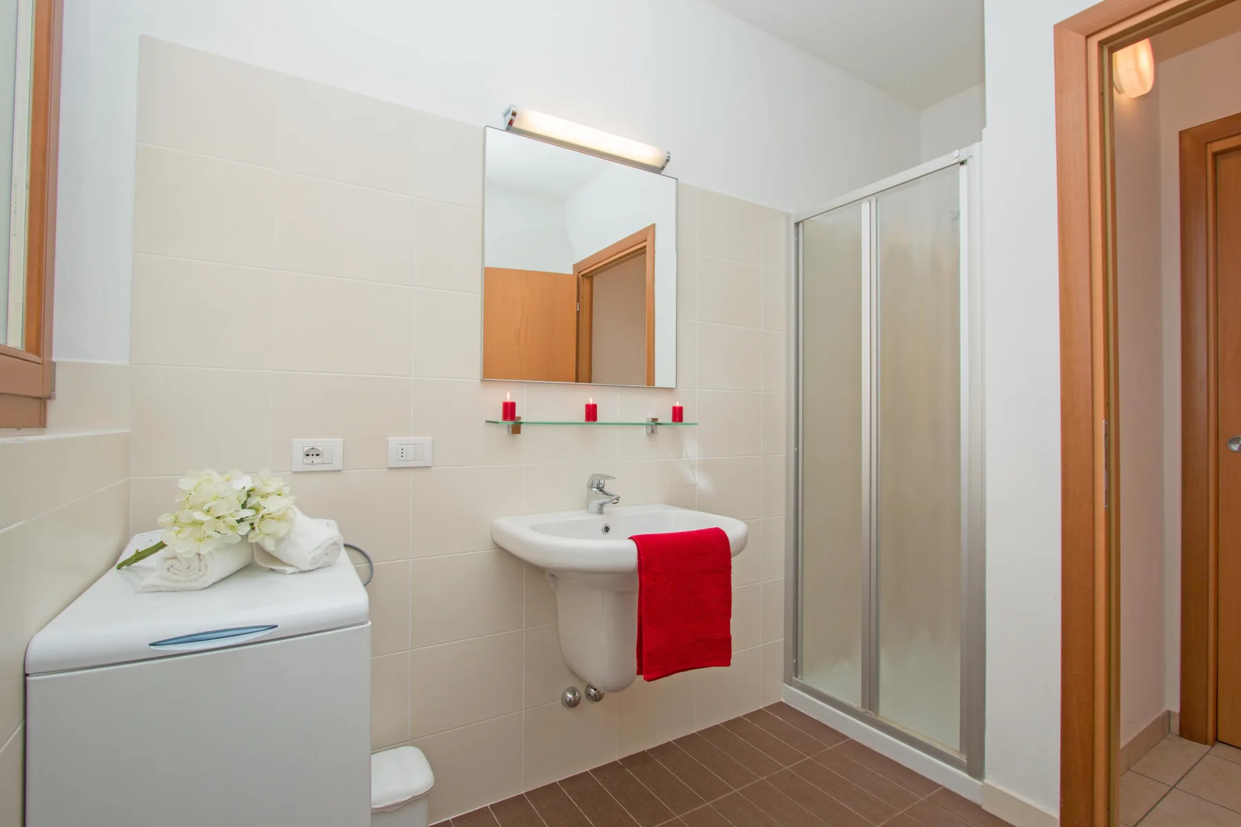 A bright bathroom with a sink, mirror, and glass shower.