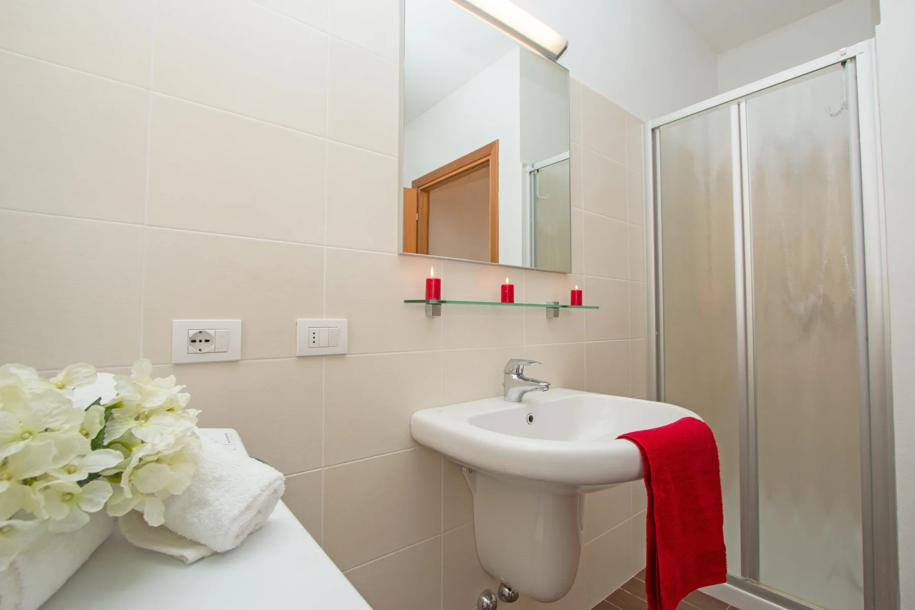 A tiled bathroom with a sink, mirror, and shower.