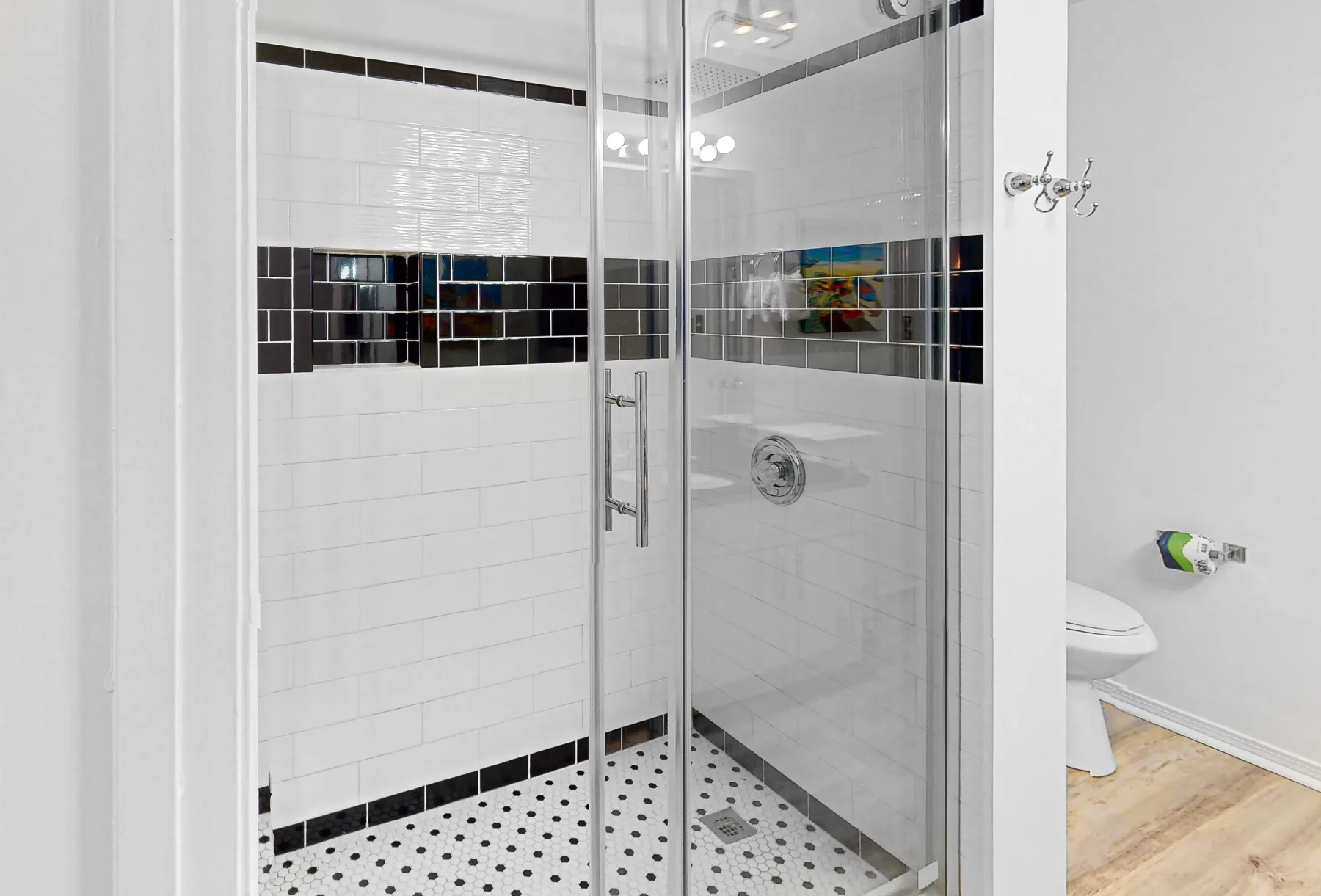 Un baño alicatado con ducha de cristal y suelo estampado.