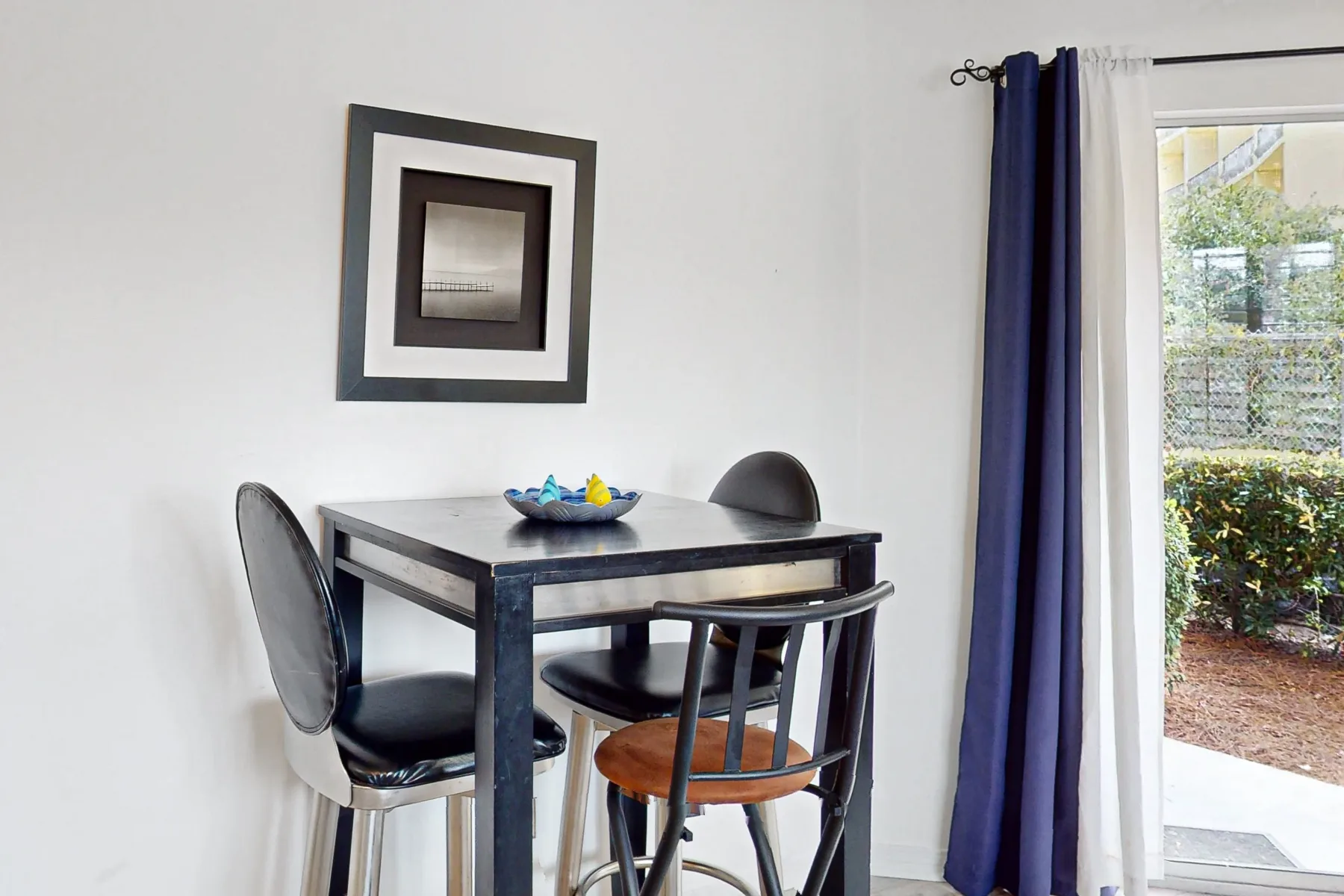 Comedor con una mesa oscura y sillas junto a una puerta de vidrio.