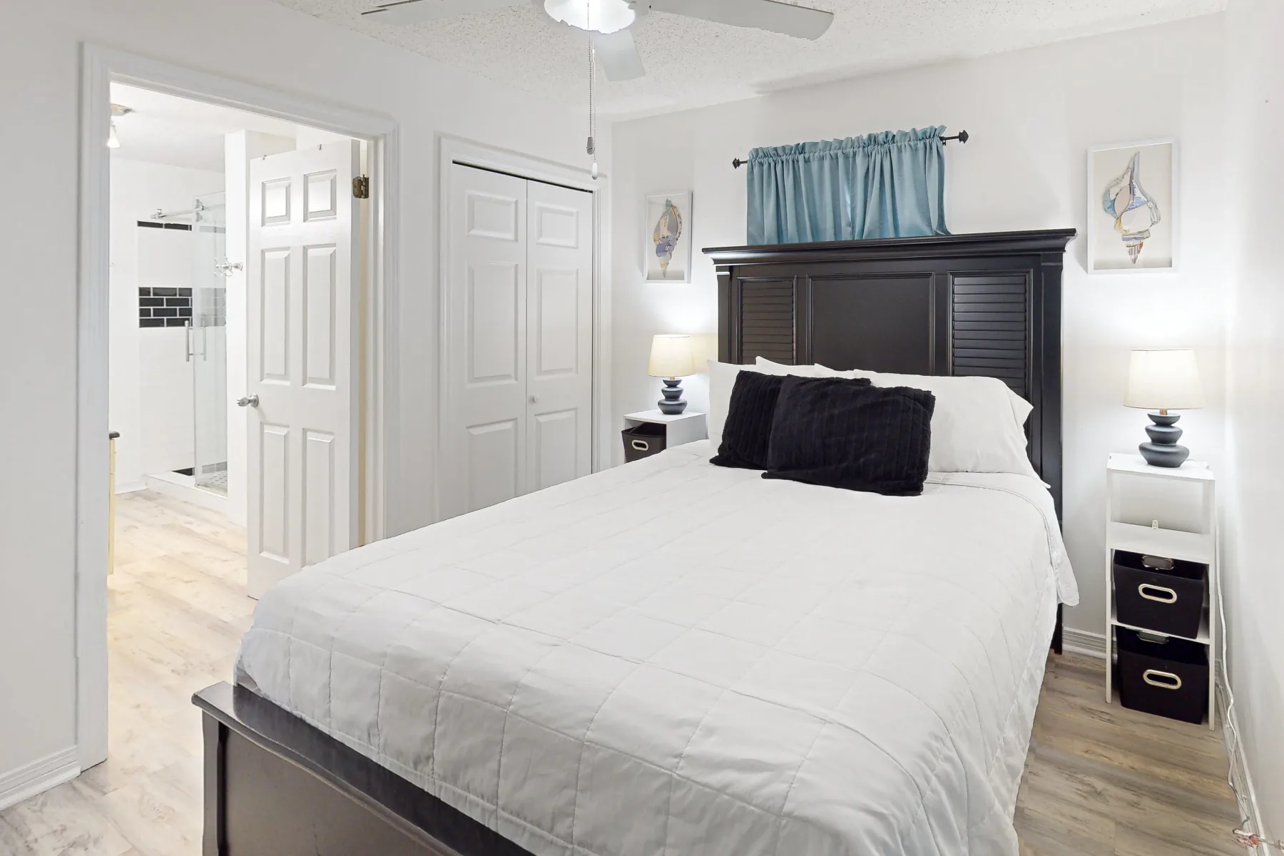 Un dormitorio luminoso con una cama grande, un cabecero oscuro y cortinas azules.