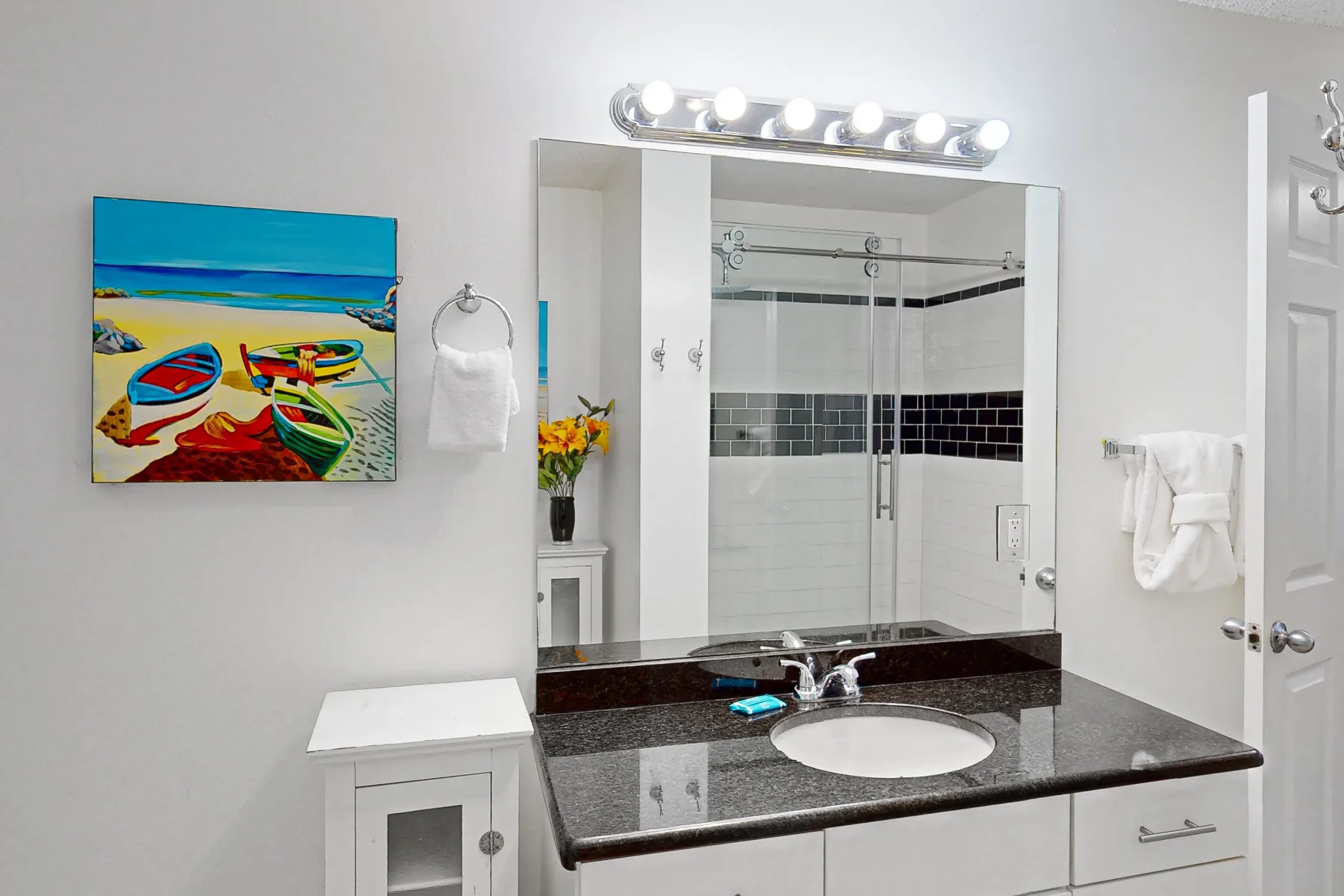 Un lavabo de baño con un espejo amplio y una ducha de vidrio detrás.