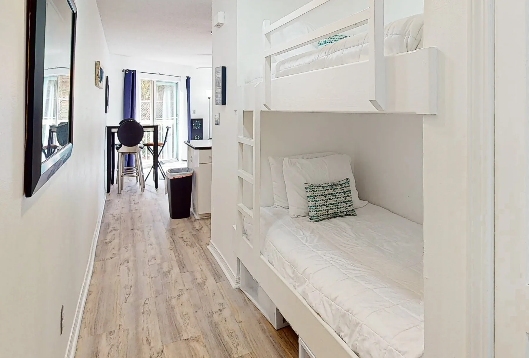 Una habitación luminosa con literas blancas y un pequeño comedor.