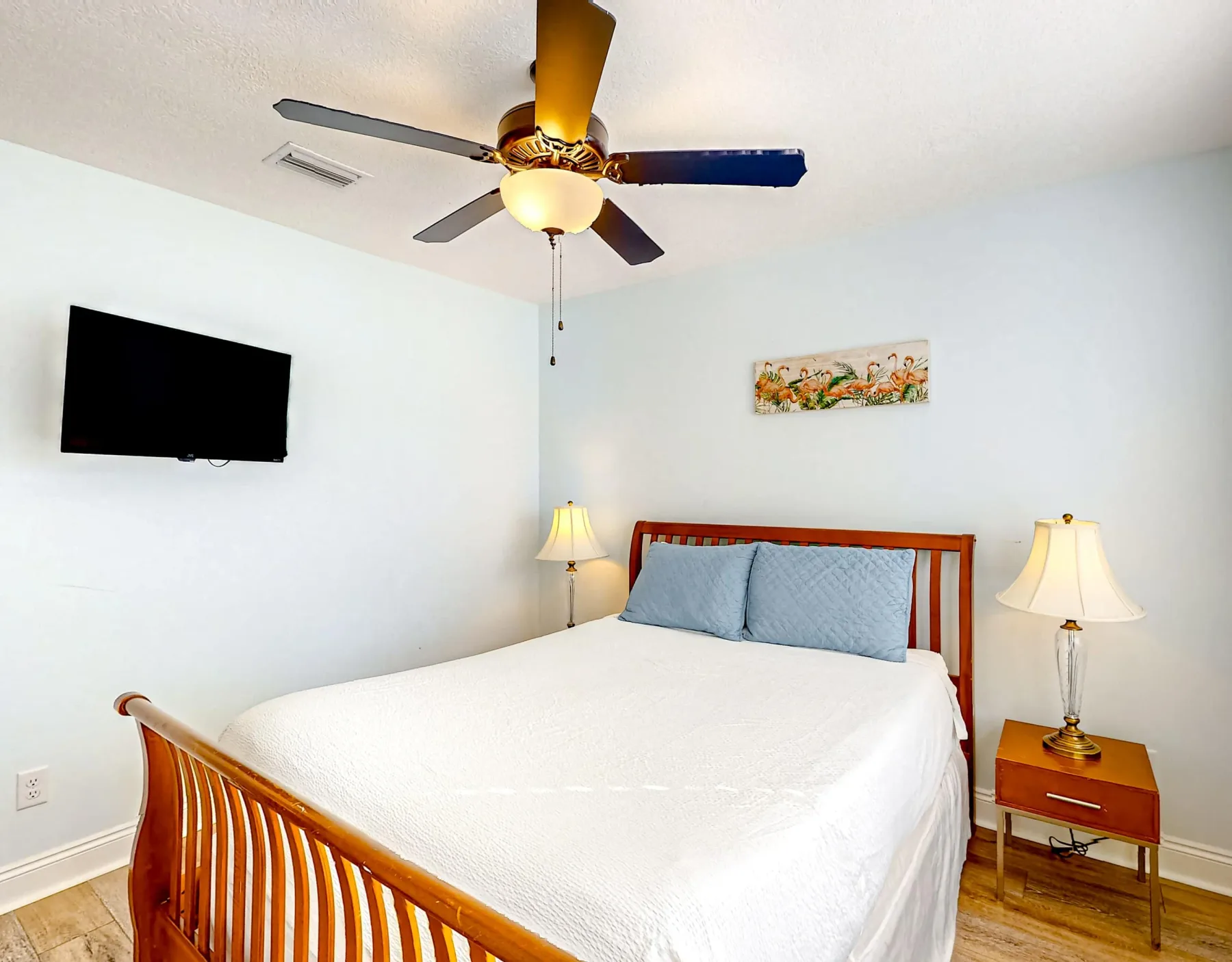 Un dormitorio con una cama, mesitas de noche y un televisor en la pared.