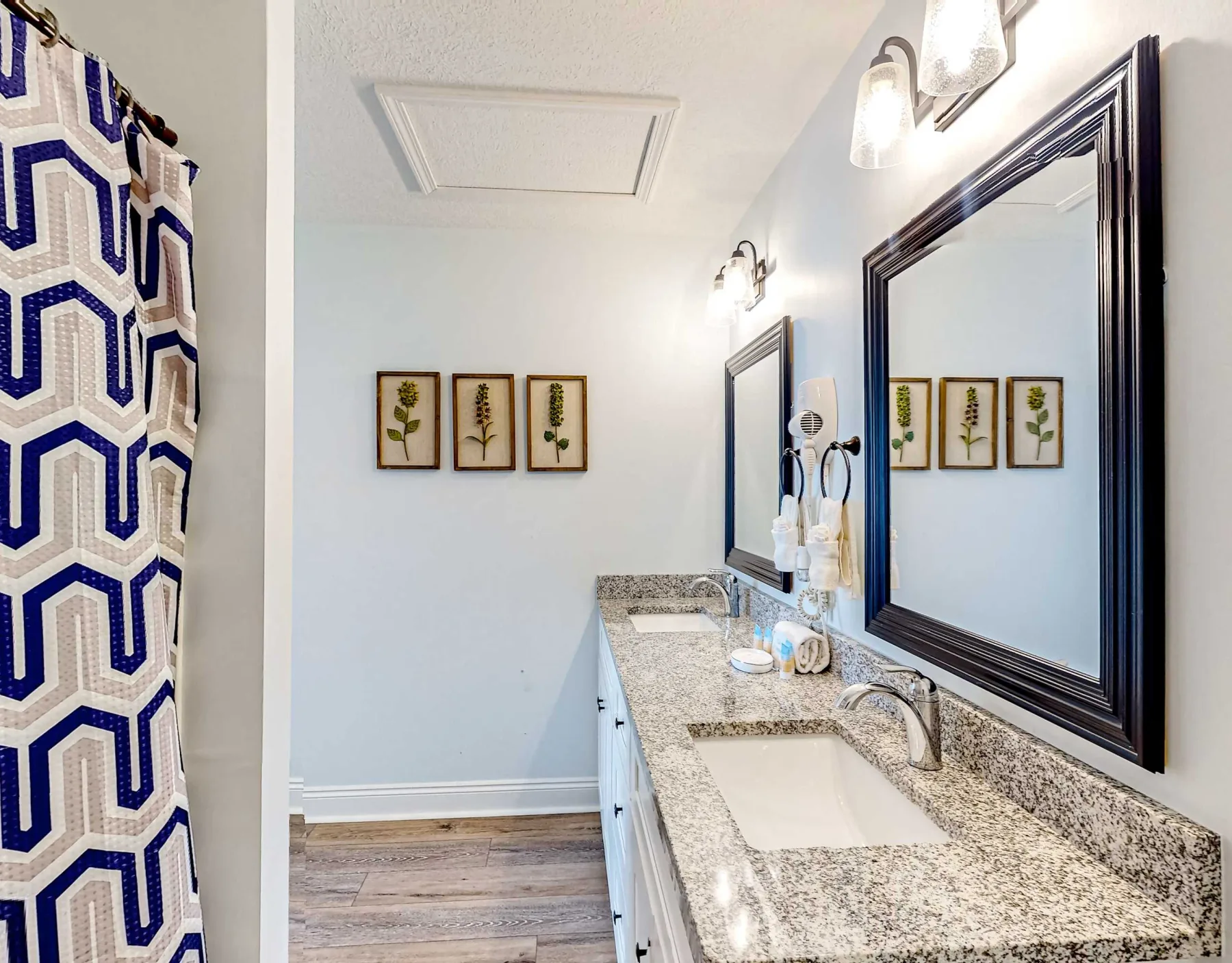 Un tocador de baño con lavabo y una cortina de ducha estampada.