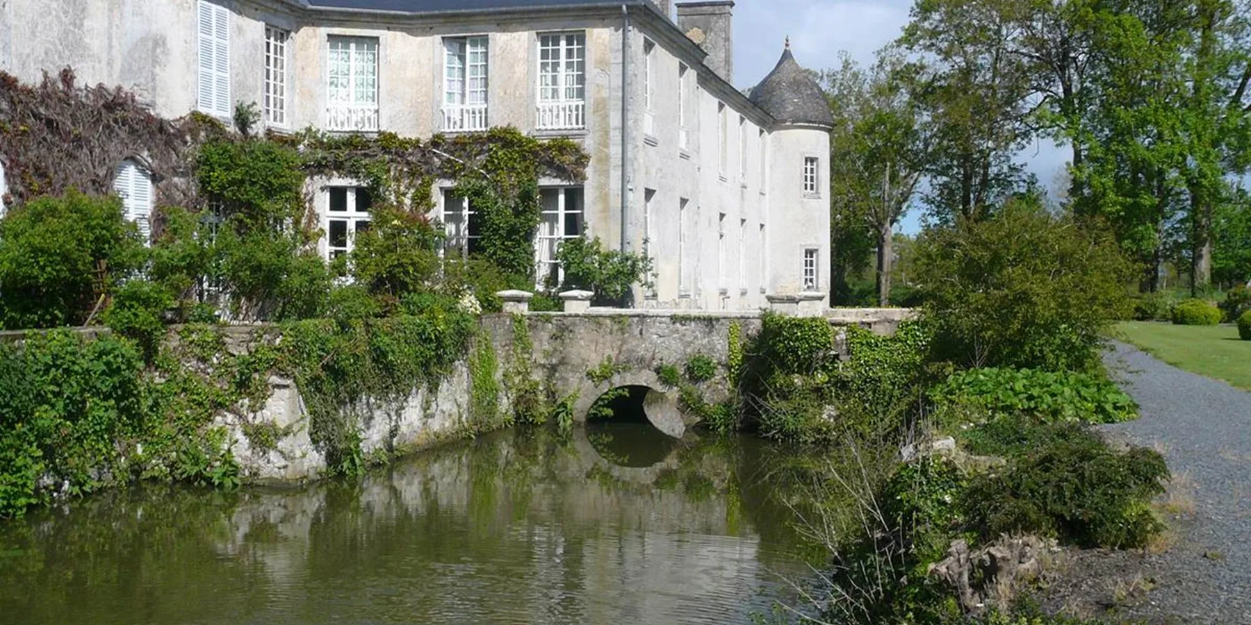 Representative hotel space: A stone building stands beside a small stream and landscaped grounds.