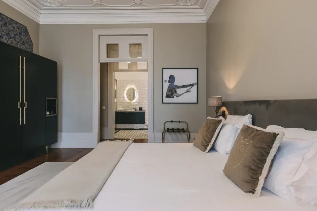 Espacio representativo del hotel: Un dormitorio con la cama tendida y un baño visible a través de la puerta.