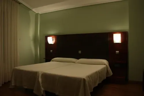 Representative hotel space: A bedroom with two beds beneath a dark headboard and wall lights.