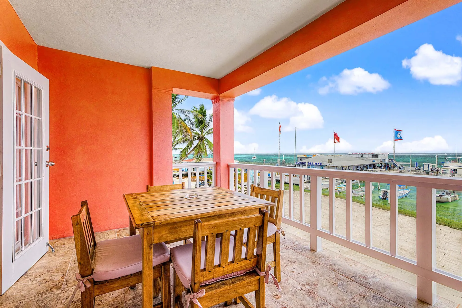 Espacio representativo del hotel: Un balcón cubierto con una mesa de comedor de madera da a la playa y al mar.