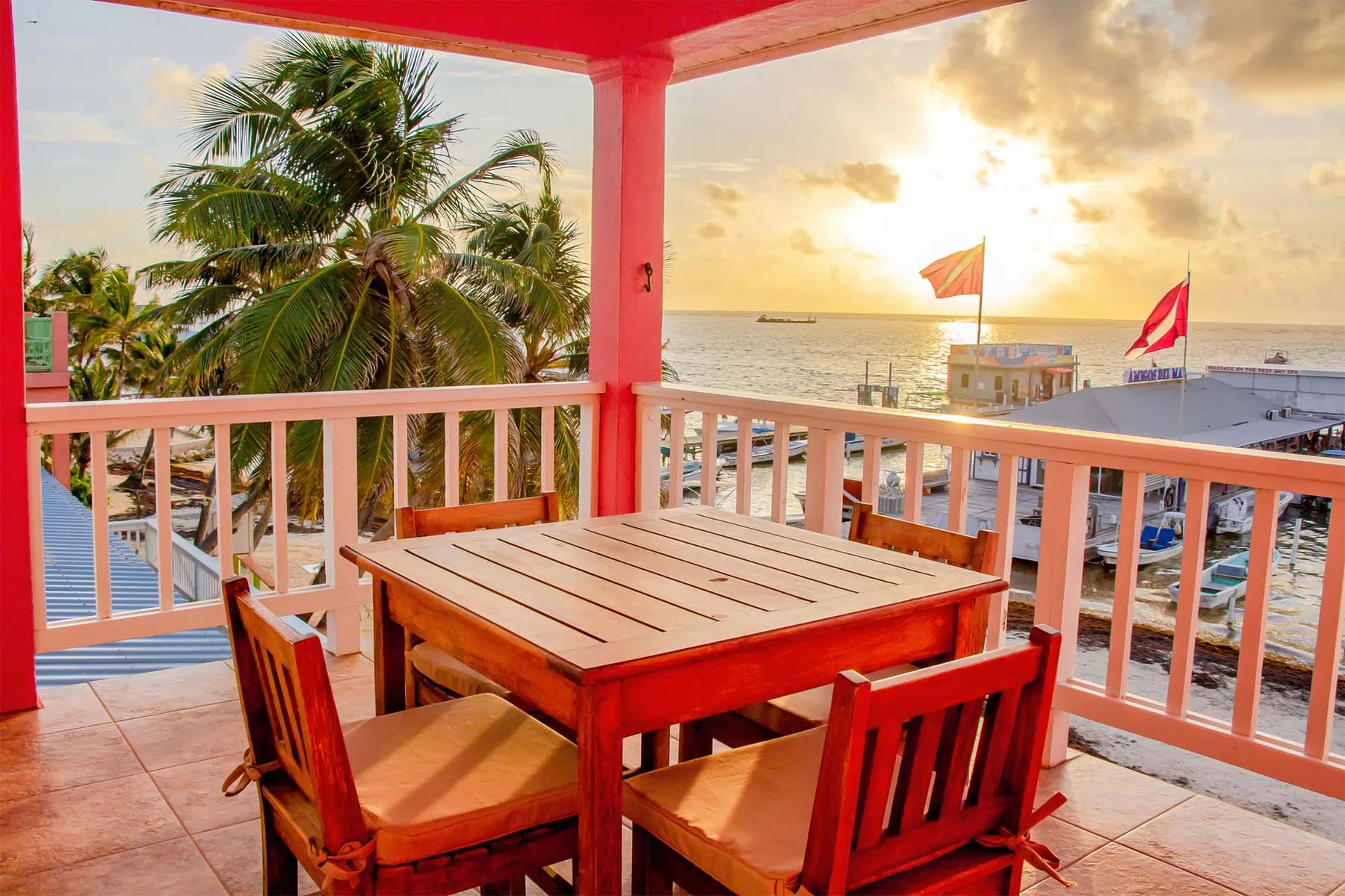 Espacio representativo del hotel: Un balcón cubierto junto al mar tiene una mesa de comedor de madera y sillas frente al agua.