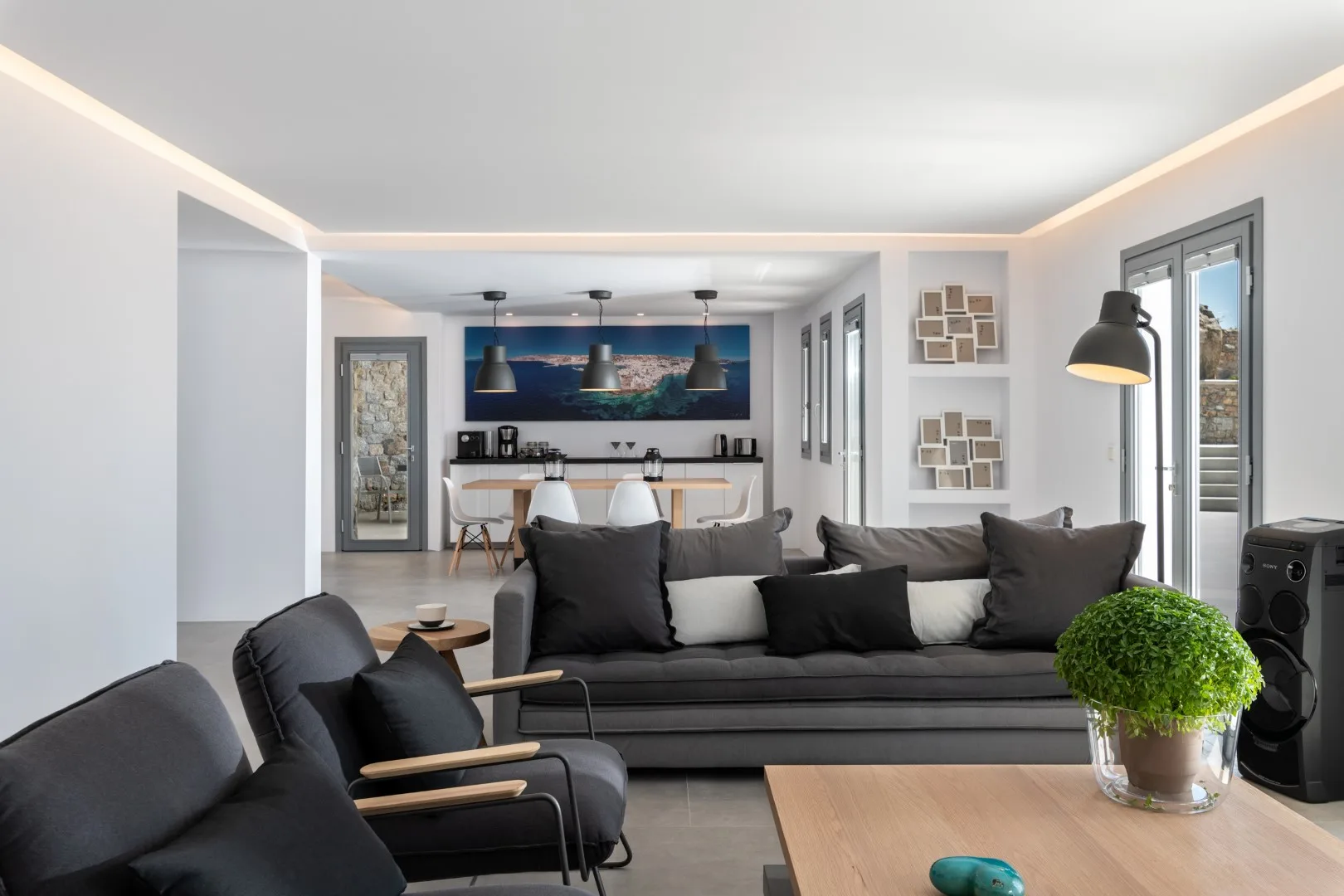 A modern living room with dark seating and an open kitchen in the background.