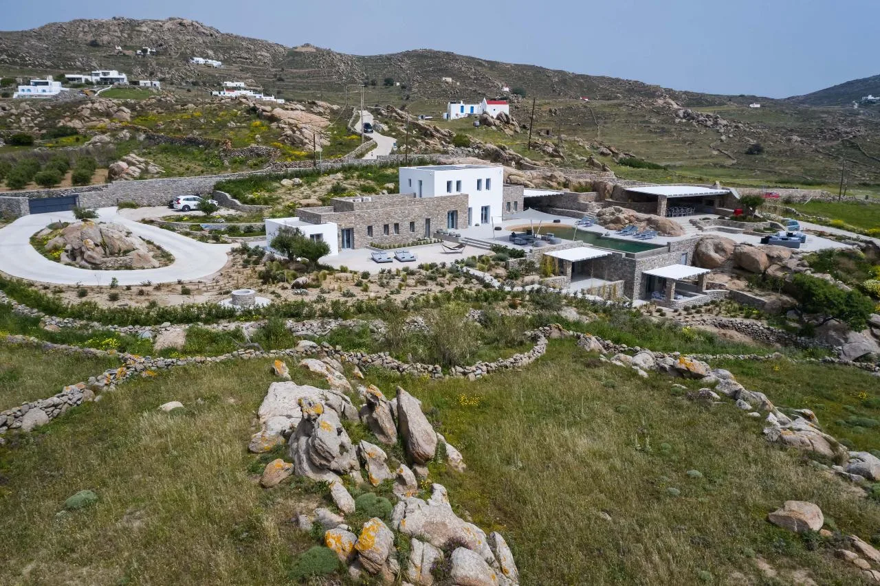A modern building sits among rocky hills and sparse vegetation.