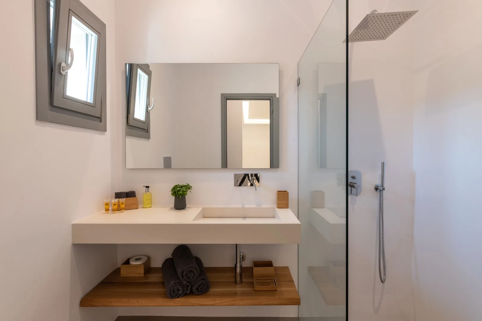 A bright bathroom with a sink, wall mirror, and glass shower.