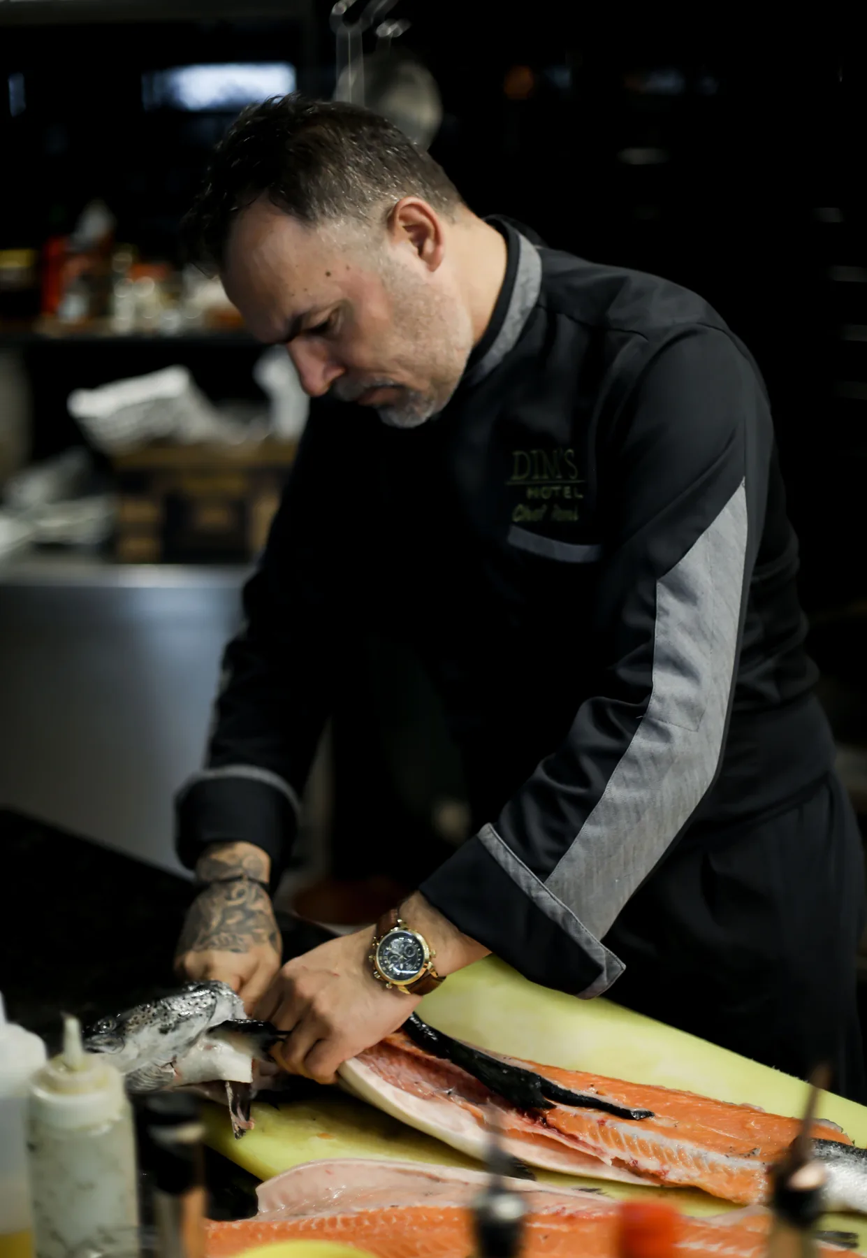Espacio representativo del hotel: Un chef prepara un filete de salmón sobre una tabla de cortar en una cocina.