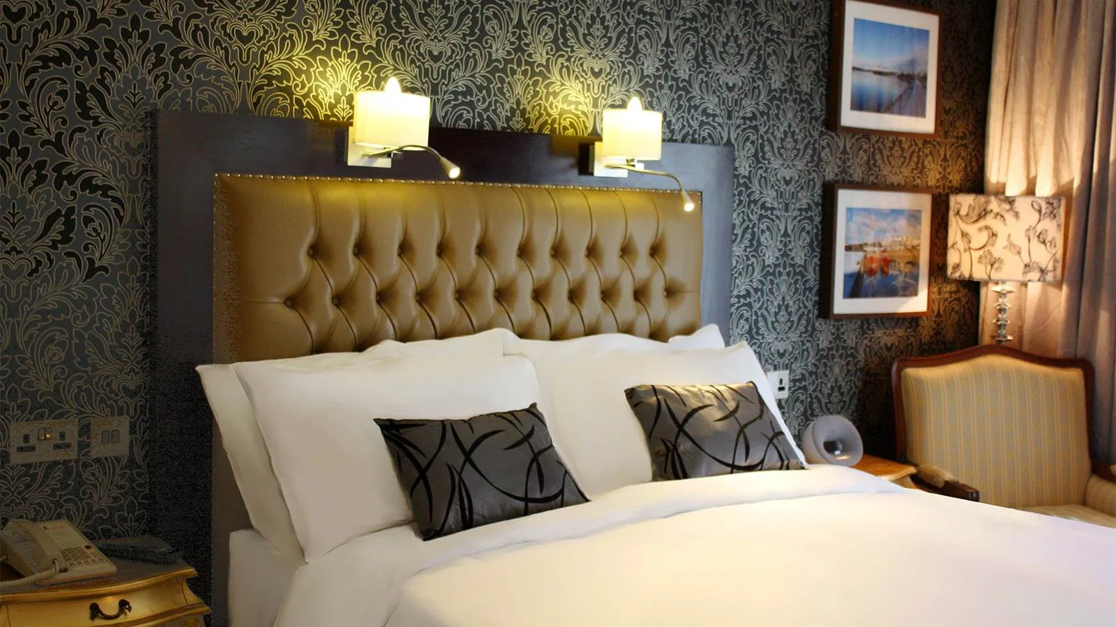 Espacio representativo del hotel: Un dormitorio de hotel con cabecero acolchado, ropa de cama blanca y lámparas de noche.