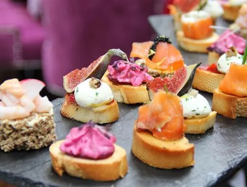 Espacio representativo del hotel: Una variedad de pequeños aperitivos salados está dispuesta en una bandeja.