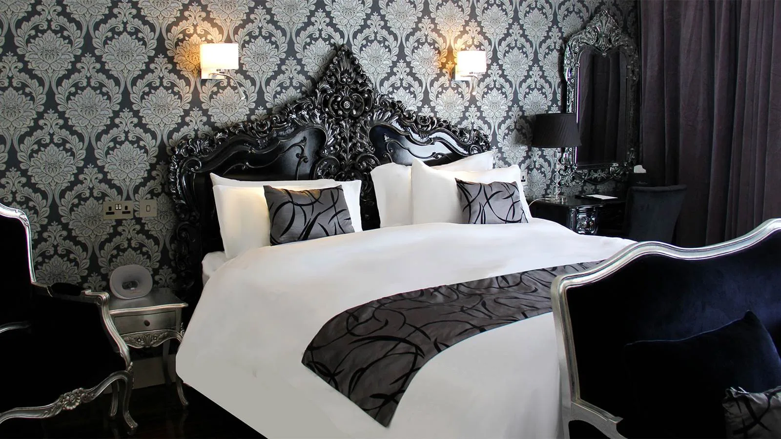 Espacio representativo del hotel: Un dormitorio con una cama grande y papel tapiz estampado.