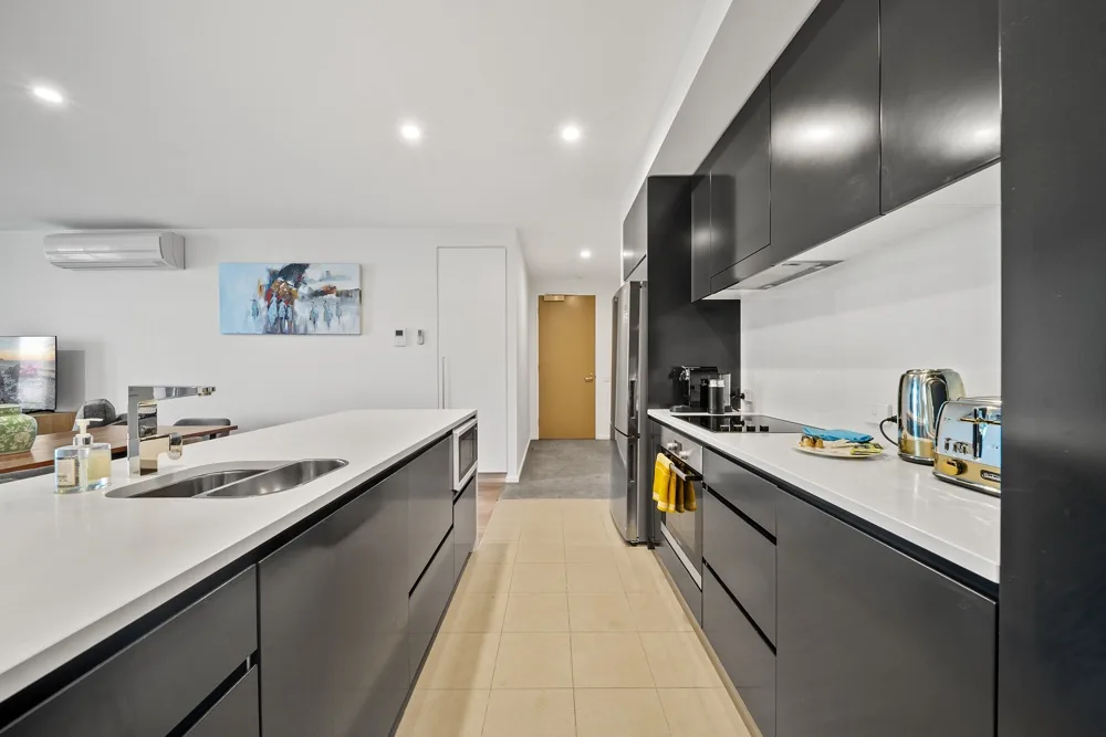 Una cocina moderna con gabinetes oscuros, encimeras blancas y una isla central.