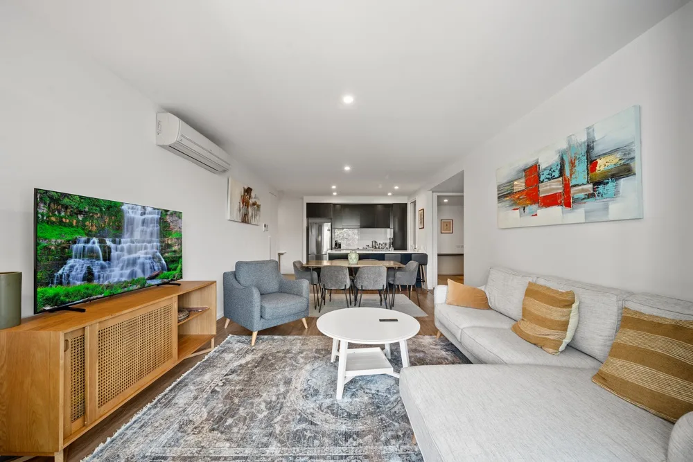 Una sala luminosa con asientos, una mesa de centro y un televisor.