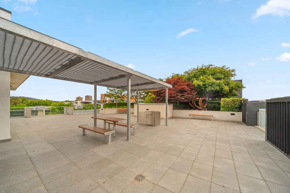 Zona común: Una terraza al aire libre con una zona de estar sombreada y jardineras.